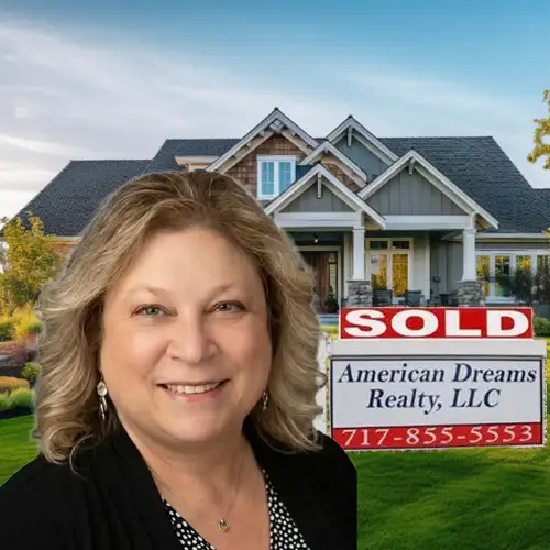 Smiling real estate agent in front of a house with a red SOLD sign and a American Dreams Realty LLC sign showing